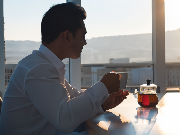 Successful businessman sitting at the table and drinking tea in the morning sun